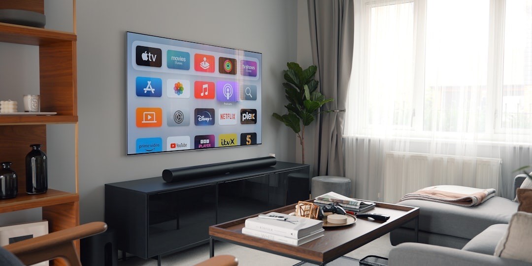A living room setting shows a black soundbar, placed beneath the TV on a TV stand.
