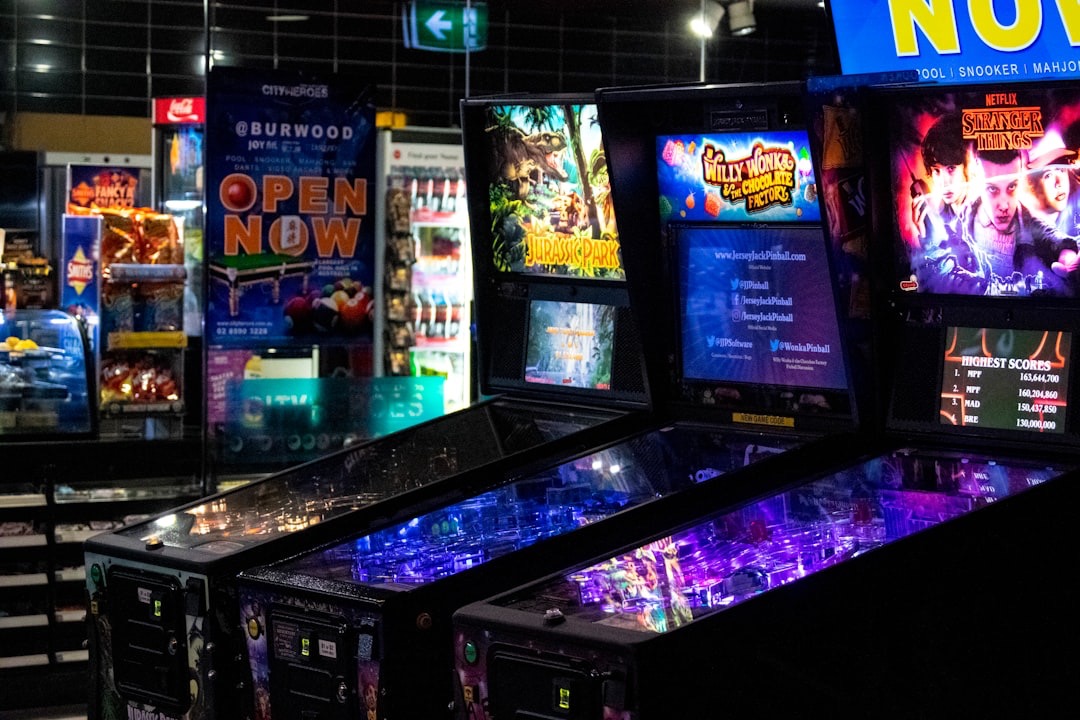 1980s-style arcade with glowing machines, one featuring the Stranger Things cast